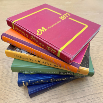 A rainbow stack of Michigan yearbooks, representing LGBTQ+ Michigan history.