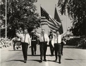 William Milliken walks in a parade with George Romney and Robert Griffin