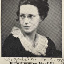 Woman in black dress with white collar wearing glasses, looking off to the left.