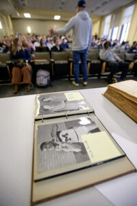Scrapbook on a table in the foreground and a class in a lecture hall in the background. 