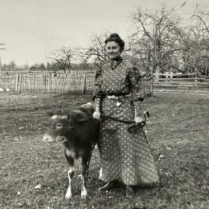 A woman standing with a calf on a farm