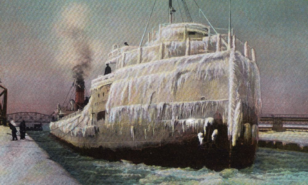 An archived postcard of the Edmund Fitzgerald locking down in December after a seventy-two hour battle with a zero storm on Lake Superior, coated in ice, and floating on the water.