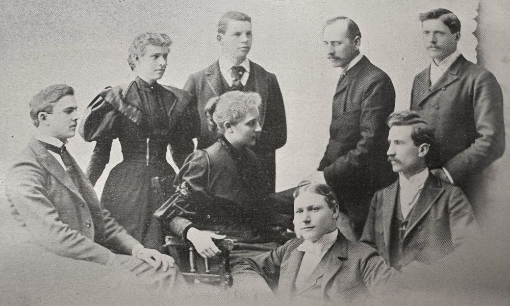 Gertrude Buck as president of the Oratorical Association, seated in the middle of a group portrait of men and women wearing formal suits and dresses.