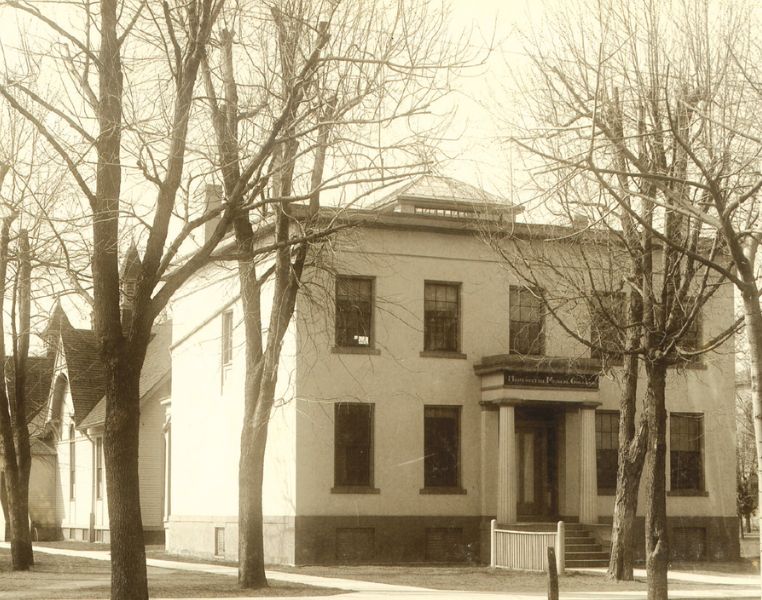 Northeast Professors' House, a building with a sign that says "Homeopathic Medical College," next to trees.