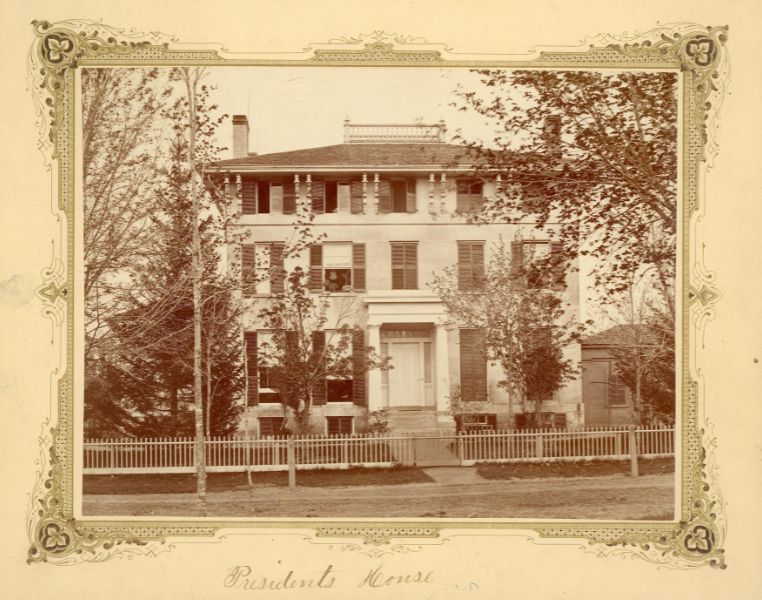 Southwest Professors' House, a building featuring windows with shutters, a long walkway, a fenced yard, and trees.