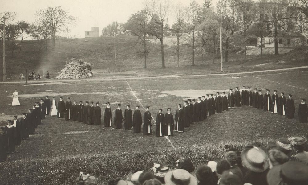 The first Women's Field Day at U-M in 1910, featuring women standing in the shape of a block "M" on Palmer Field next to a pile of bonfire wood.