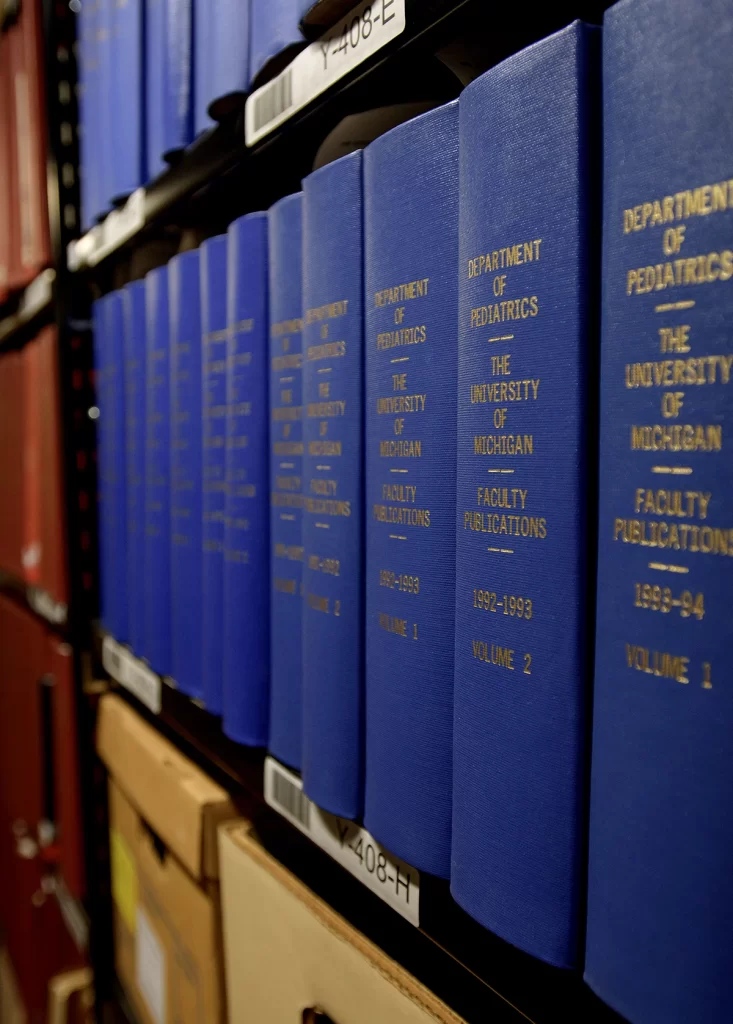 Several blue books lining a shelf in the stacks of the Bentley Historical Library.