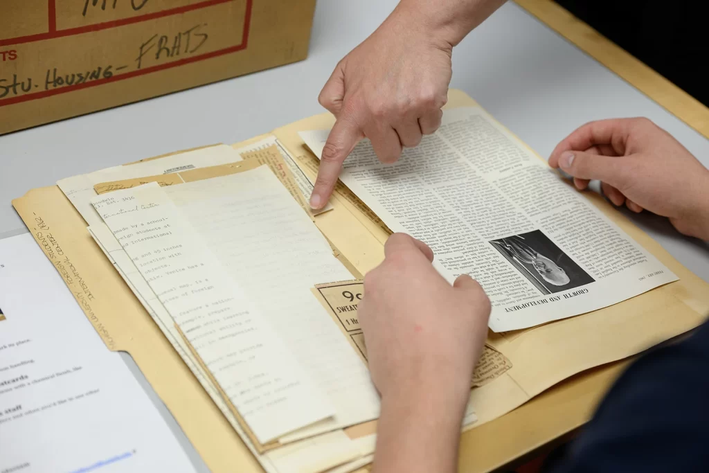 A finger points to papers in a folder.