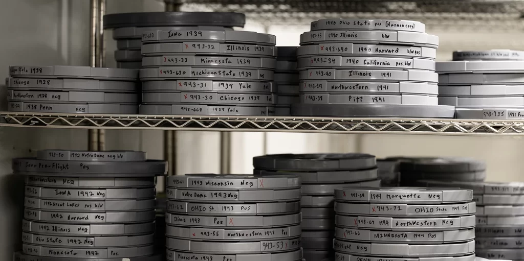Historical film reels stacked on white metal shelves in the Bentley Historical Library's Cold Room.