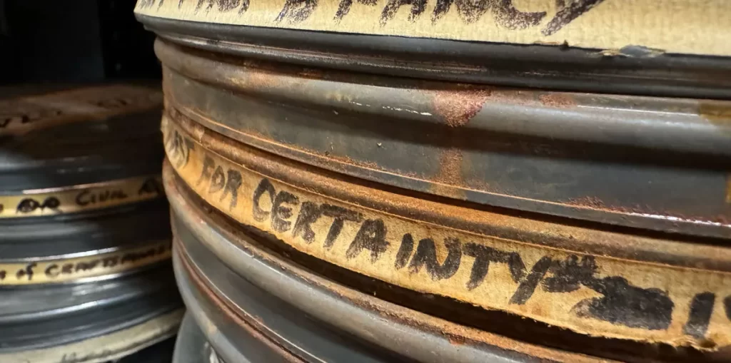 A stack of old film canisters with hand-written labels.