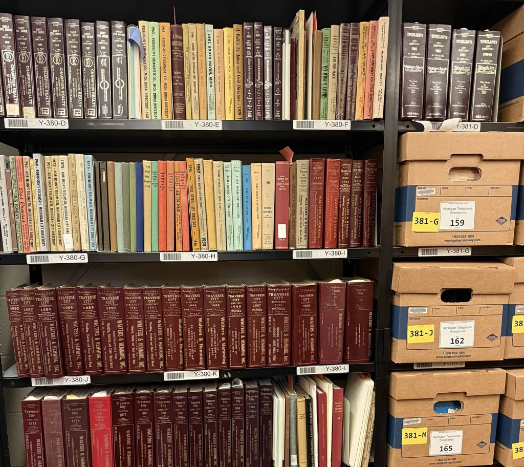 Several shelves from inside the Bentley Historical Library's stacks, holding several books on the left and boxes on the right.
