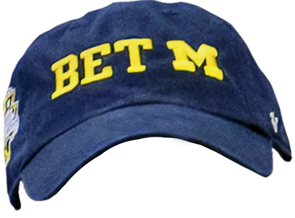 A blue hat with the rim facing forward with "Bet M" embroidered on the front in yellow.