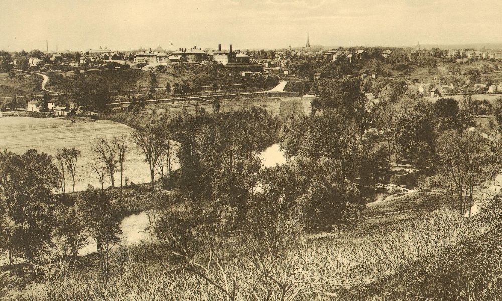 A view of Ann Arbor from the Boulevard circa 1914, around the time that Bertha Whitman arrived at U-M, featuring trees, buildings, and the Huron River.
