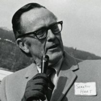 Senator Phil Hart holding a microphone and wearing glasses.