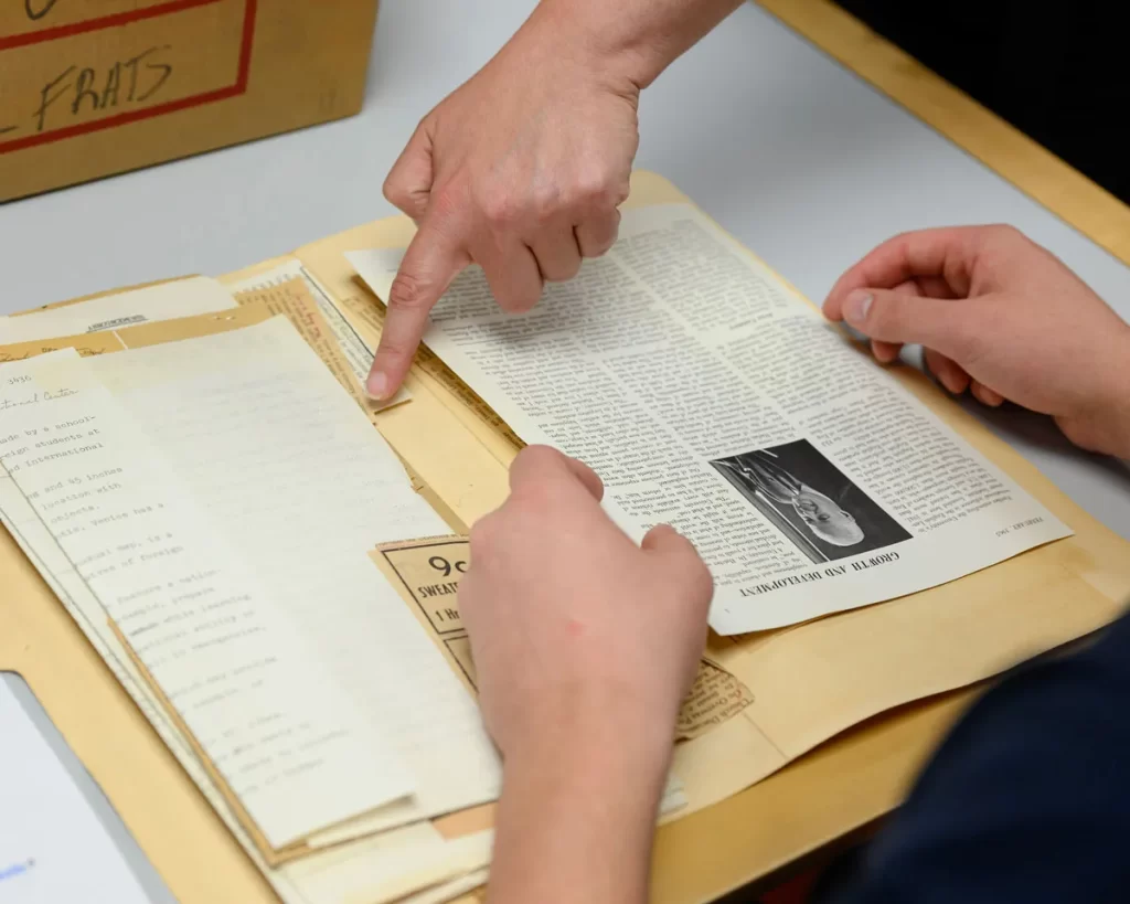 A finger points to papers in a folder.