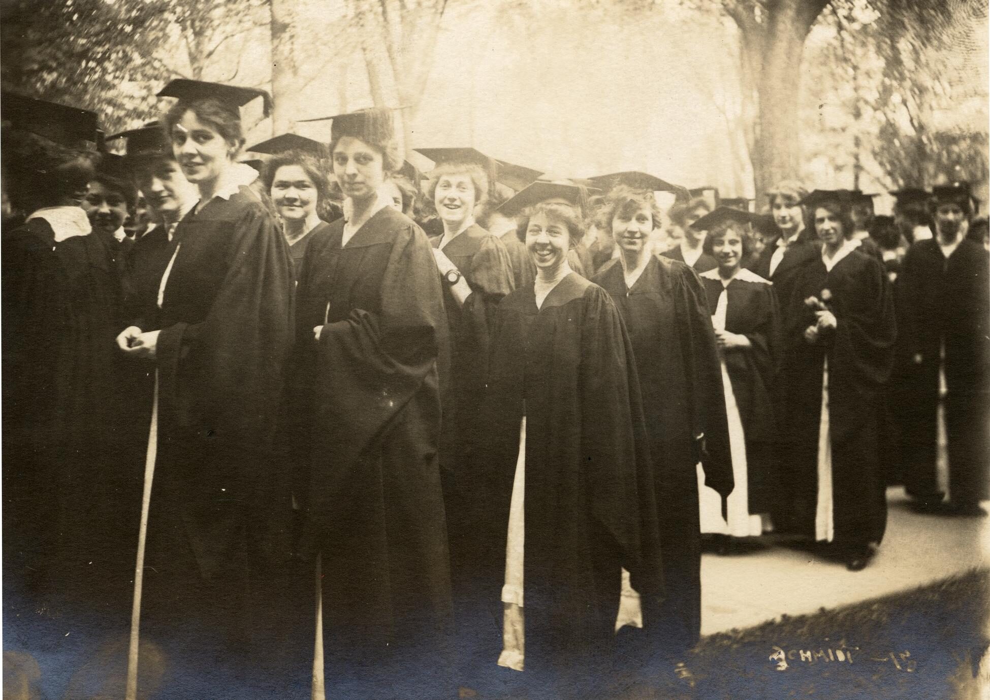 Women graduates outside in caps and gowns circa 1915.