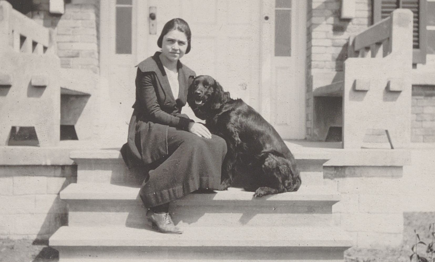 Photo of Treman and dog sitting on steps in front of her home in Nanjing, China, circa 1920.