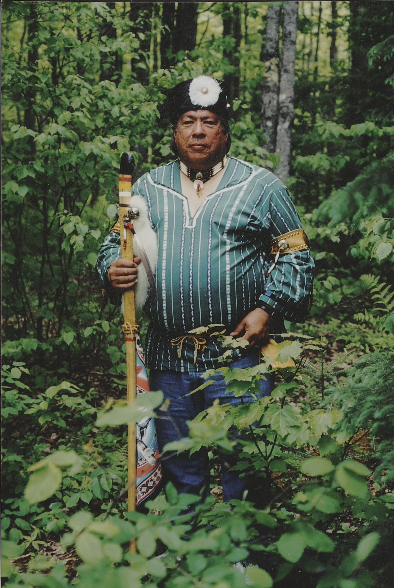 Undated photo of Warren Petosky in native dress standing in a forest.
